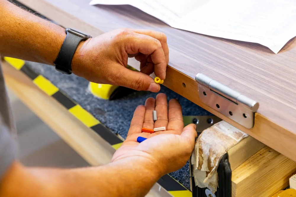 Technician checking certification plugs on the edge of a timber fire door